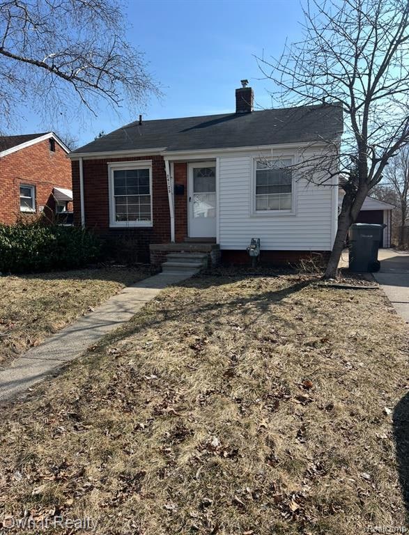 View of front of property with a chimney and brick siding