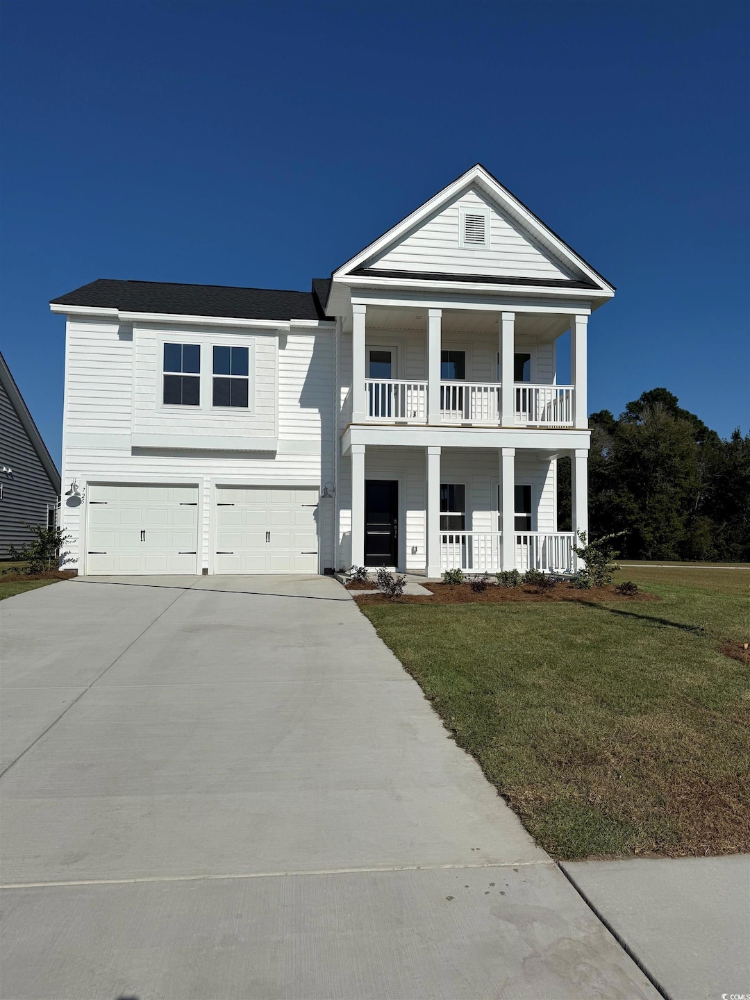 Neoclassical / greek revival house featuring a porch, driveway, a front yard, and an attached garage