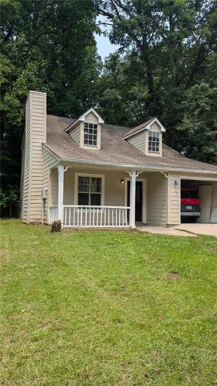 View of front facade featuring a front lawn, covered porch, roof with shingles, driveway, and a chimney