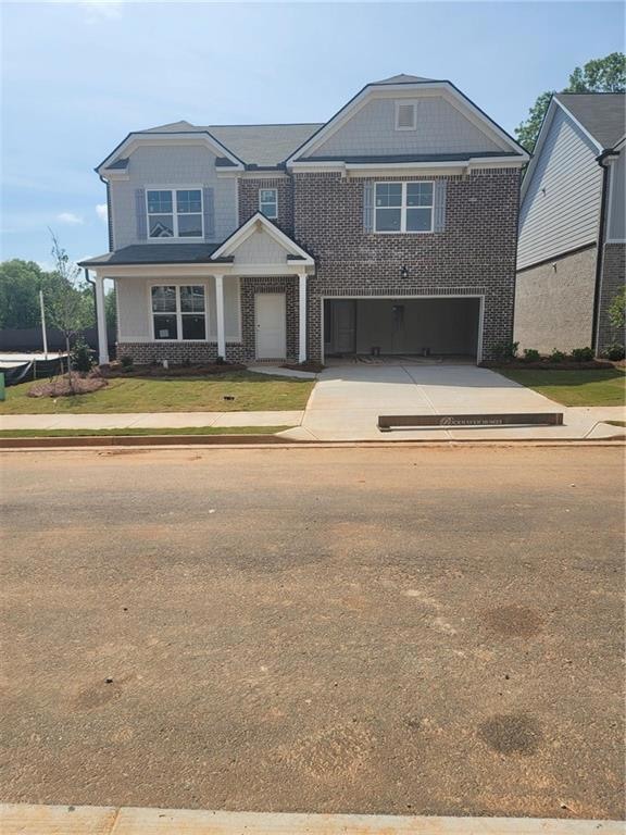 Craftsman house with concrete driveway, an attached garage, brick siding, and a front lawn