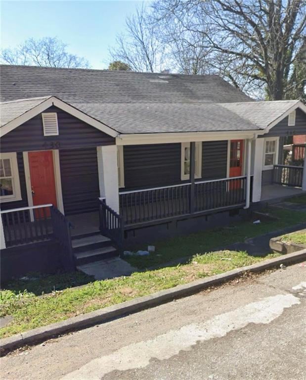 View of front of property with a porch and roof with shingles