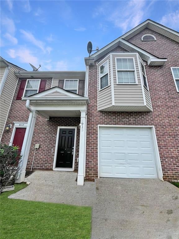 Multi unit property featuring driveway, brick siding, and an attached garage