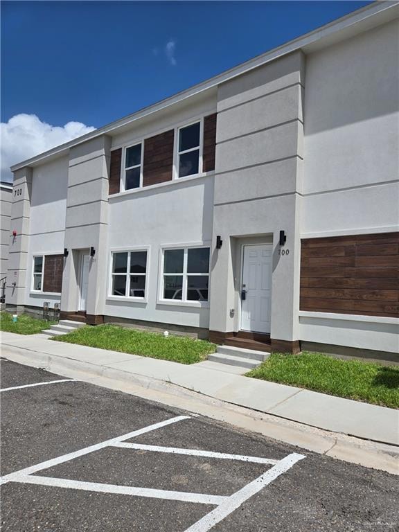 View of front facade featuring uncovered parking and stucco siding