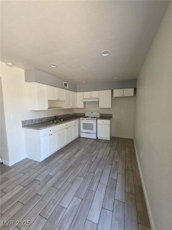 Kitchen with white electric stove, baseboards, woo