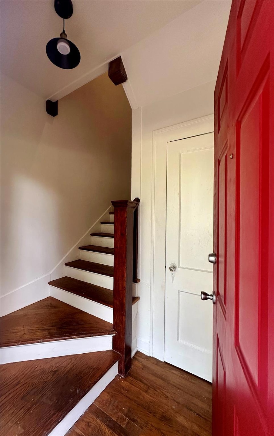 Stairs featuring wood finished floors and beamed ceiling