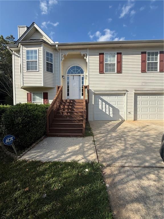 Split-level home featuring concrete driveway, and 2-car garage