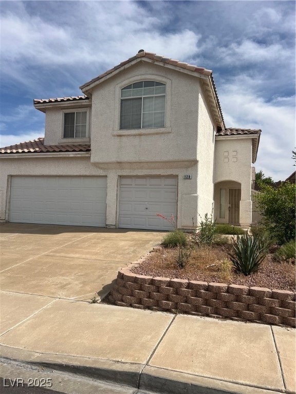 View of front of home featuring a tiled roof, a ga