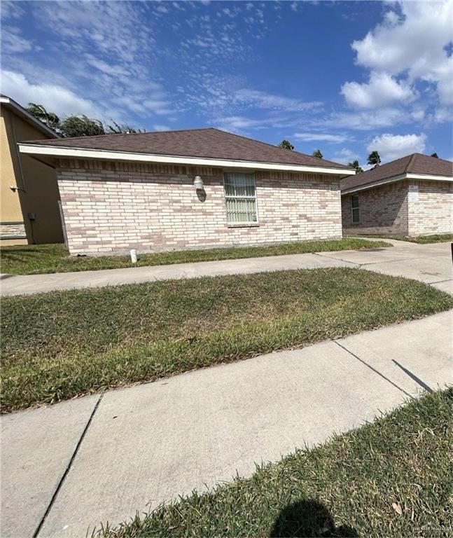 View of side of property featuring brick siding and a lawn