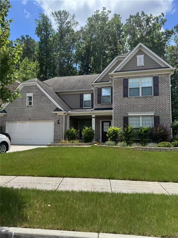 View of front facade featuring brick siding, a front yard, concrete driveway, and a garage