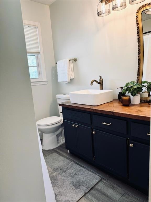 Bathroom featuring toilet, vanity, and wood-type f