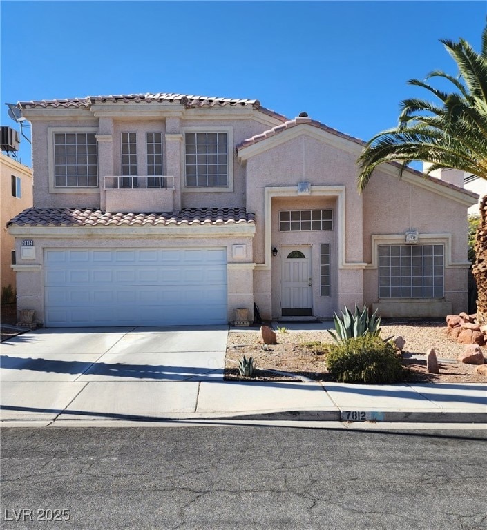 Mediterranean / spanish-style house featuring concrete driveway, stucco siding, a garage, and a tile roof