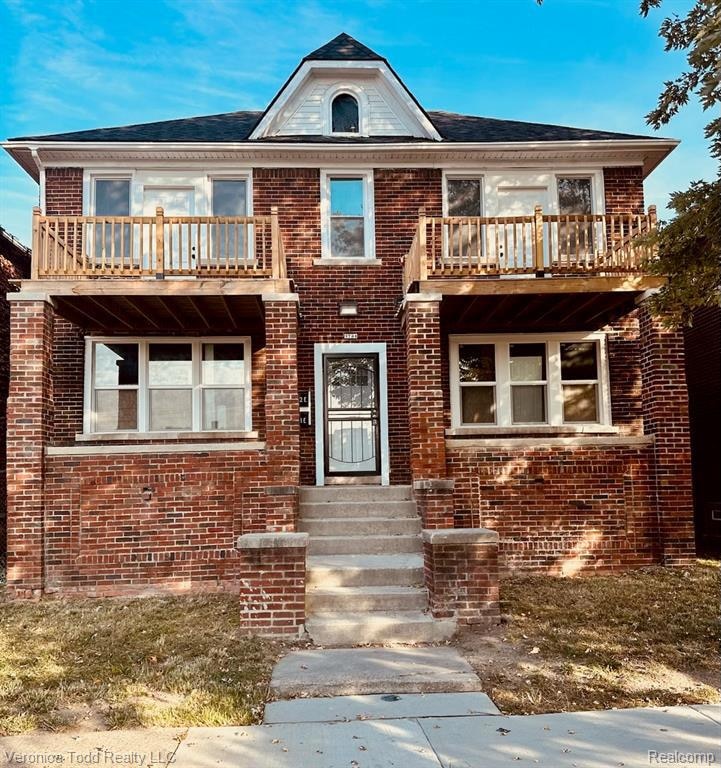 View of front of property with a balcony and brick siding