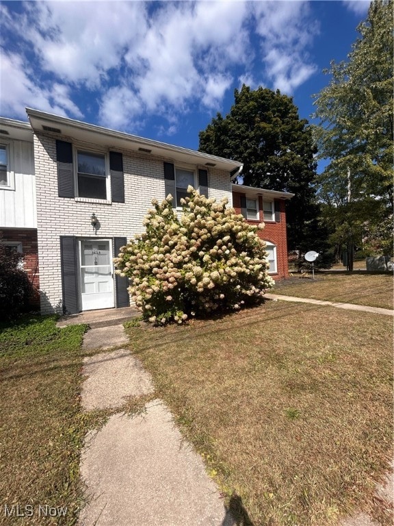View of front of house featuring brick siding and a front yard