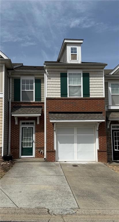 View of front of home with concrete driveway, a garage, and brick siding