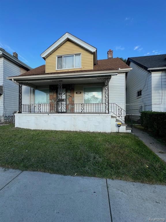 Bungalow with a front yard, a porch, a chimney, and a shingled roof