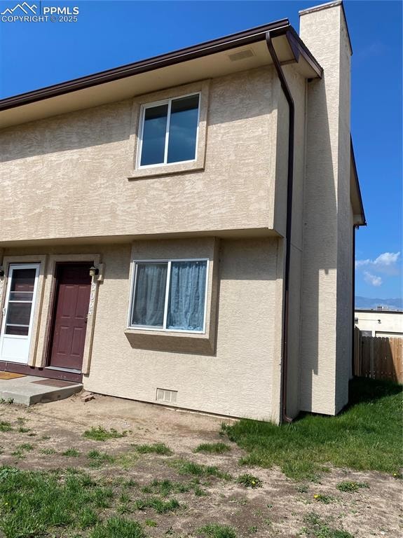 Side view of home,featuring a chimney,stucco siding and convenient covered parking.
