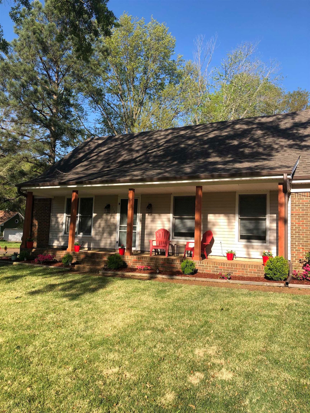 View of front of house with a porch, brick siding, and a front yard