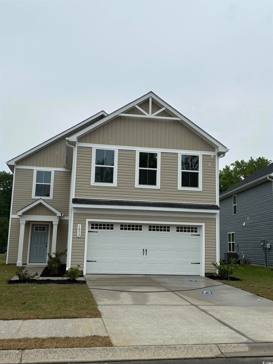 Traditional-style house featuring concrete driveway, a garage, a front yard, and board and batten siding