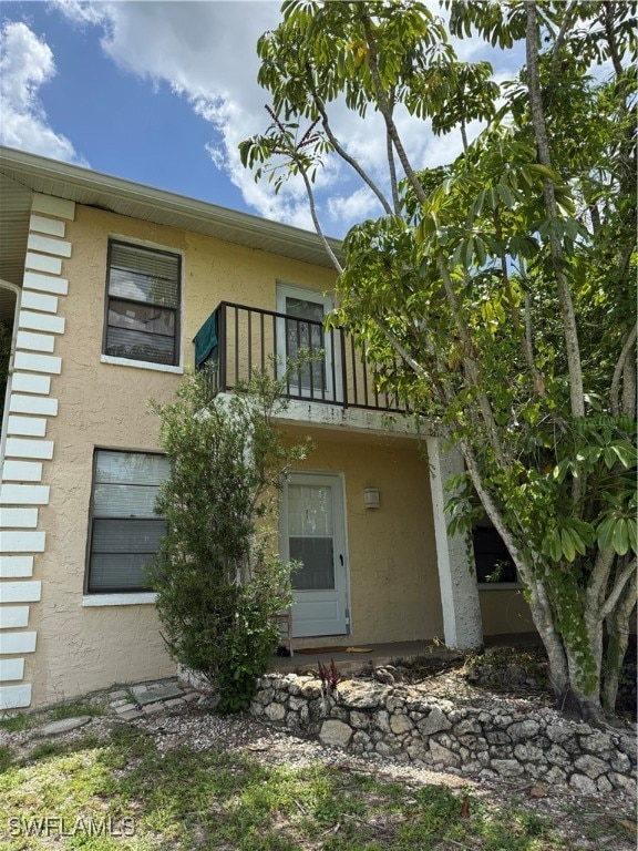 Rear view of house with a balcony and stucco siding