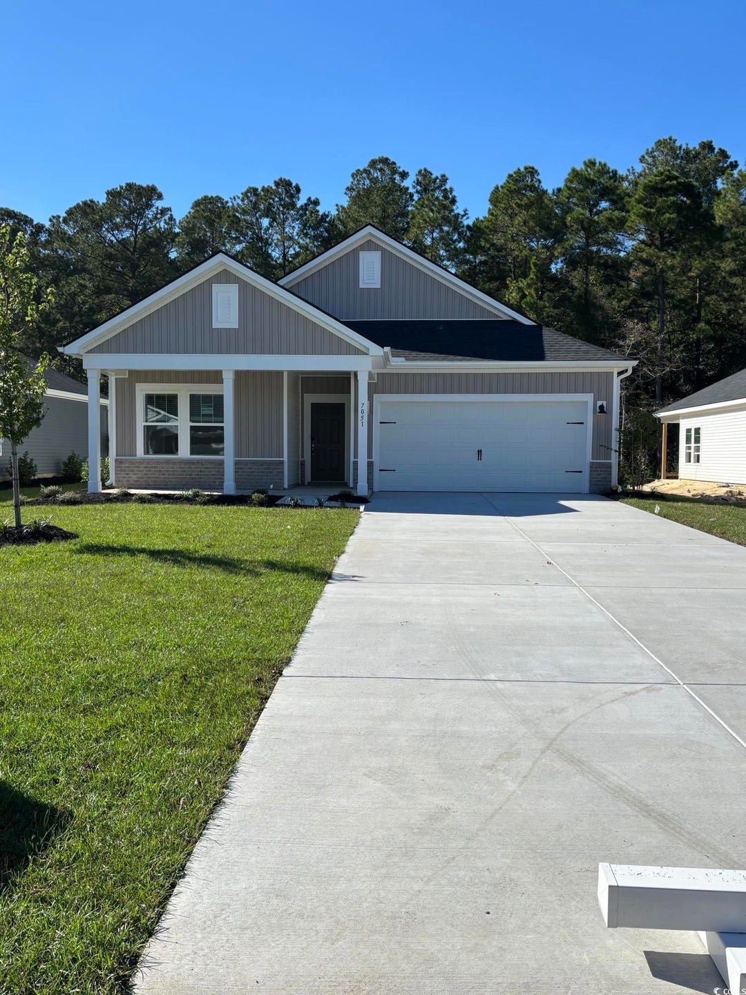View of front of house featuring a front lawn, board and batten siding, a porch, and concrete driveway