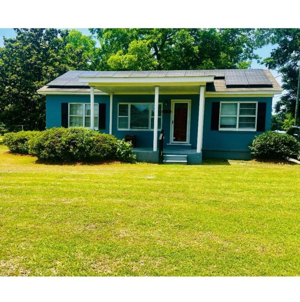View of front of home featuring roof mounted solar panels, a front lawn, and a porch