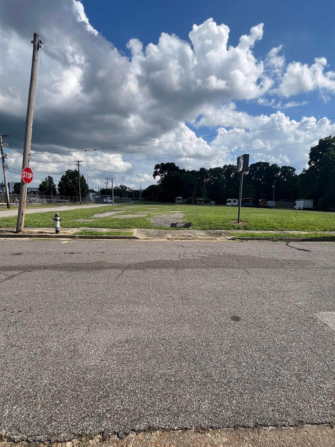 View of asphalt road with traffic signs, sidewalks, and curbs