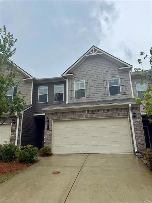 View of front of house featuring an attached garage, concrete driveway, and brick siding