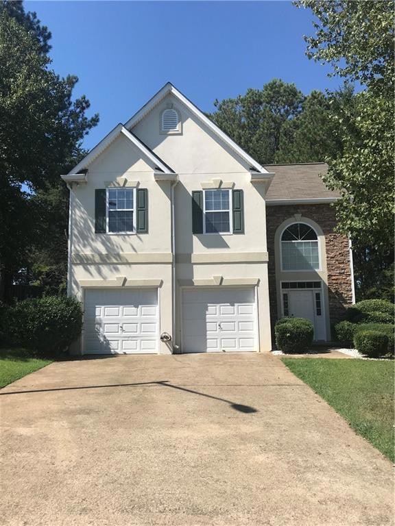 Traditional home with a garage, driveway, and stuc