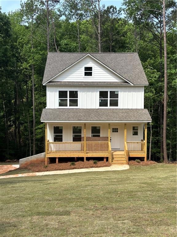 View of front of property featuring a porch, a shingled roof, a front lawn, and board and batten siding