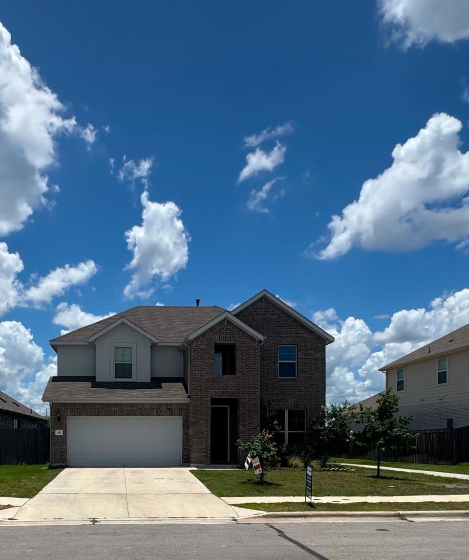 Traditional home with driveway, a garage, and bri
