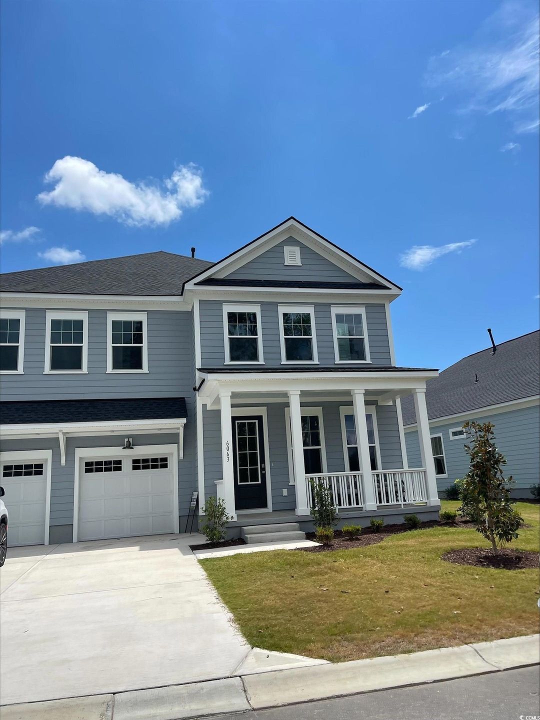 View of front of property with covered porch, a garage, and a front lawn