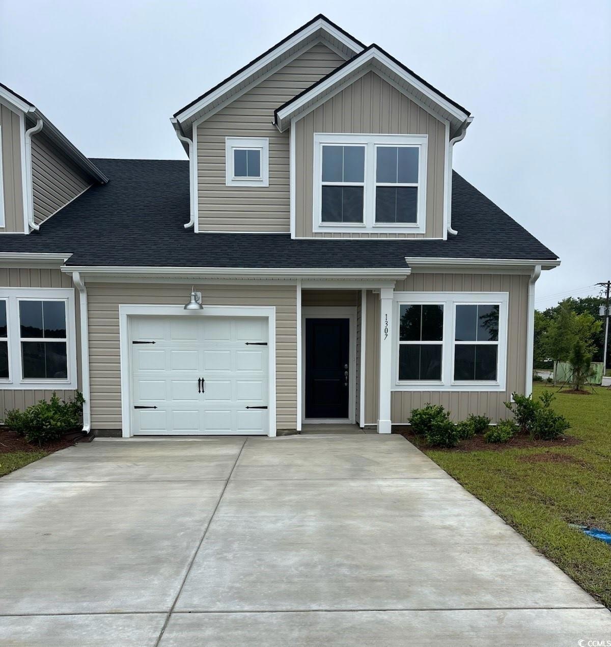 View of front facade with driveway, a shingled roof, and a garage