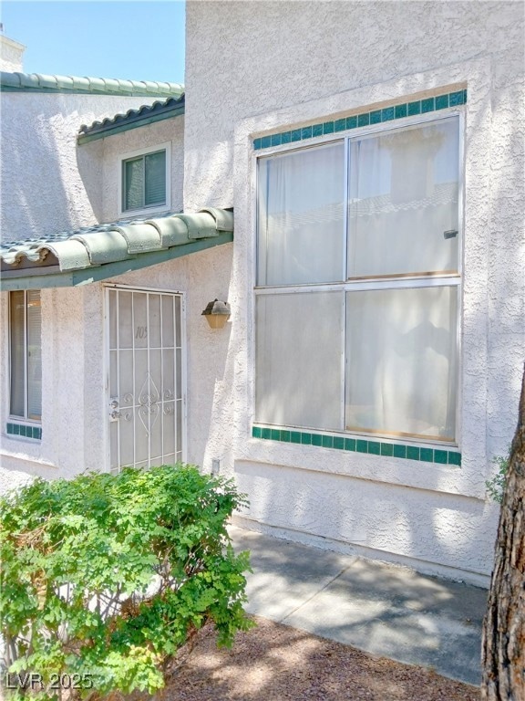 Doorway to property with stucco siding and a tile