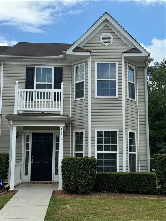 View of front of home with a front yard and a balcony