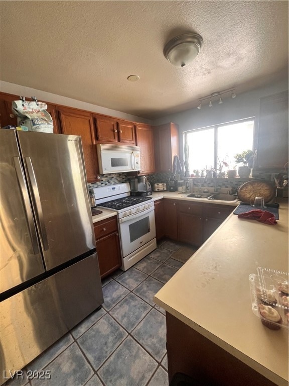 Kitchen with fridge, a sink, a textured ceiling, l