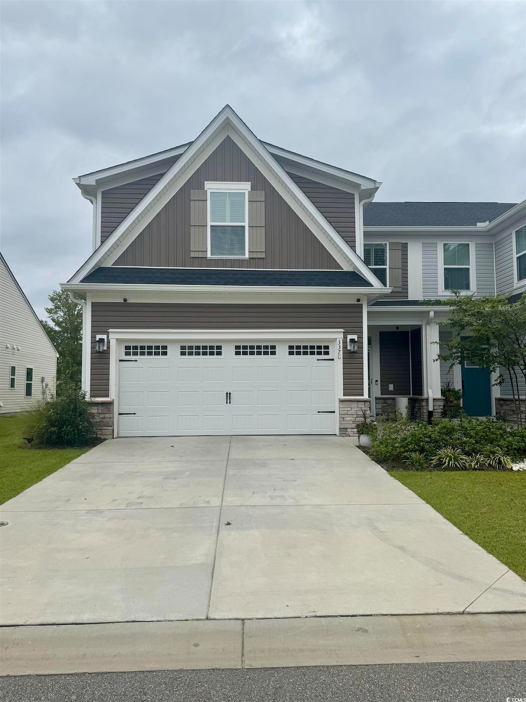 Craftsman-style house with stone siding, driveway, and an attached garage