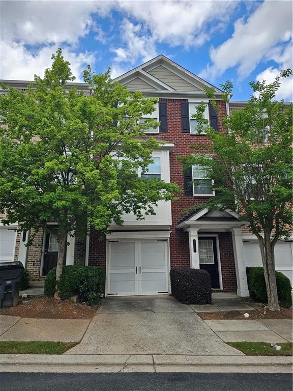 Multi unit property with brick siding, concrete driveway, and an attached garage