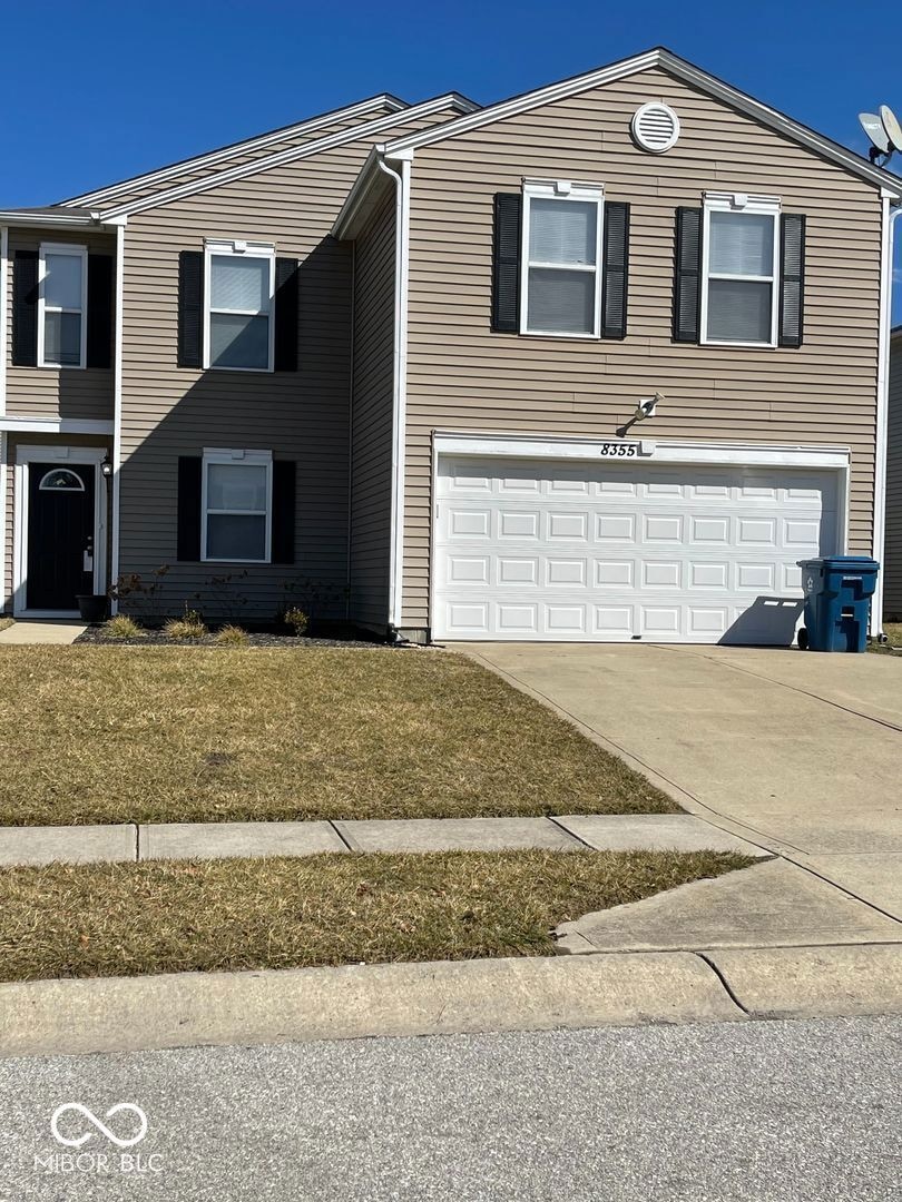 view of front of house with a garage, concrete driveway, and a front yard