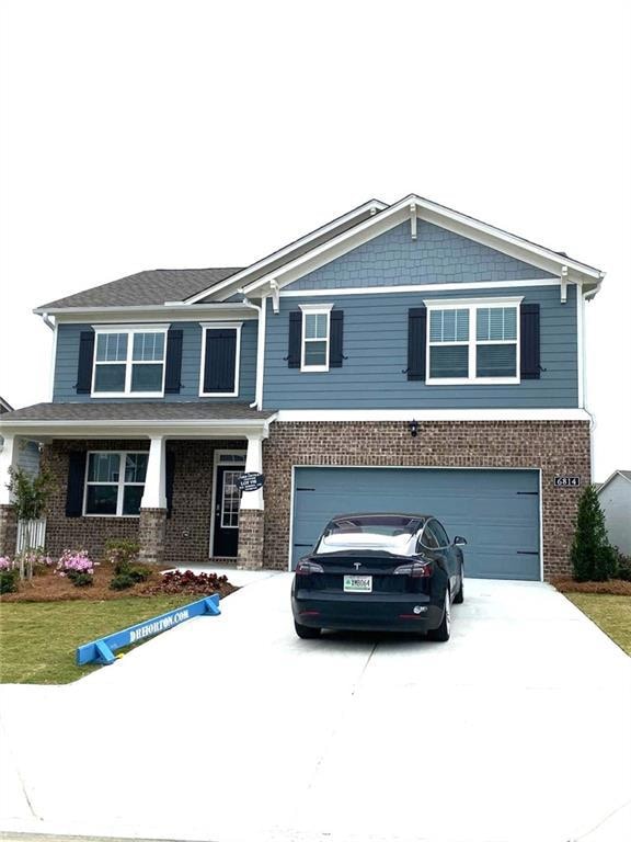 View of front of house with a garage, brick siding, and driveway