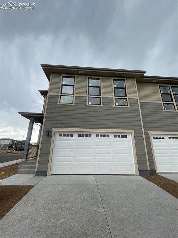 View of front of property with concrete driveway and a garage