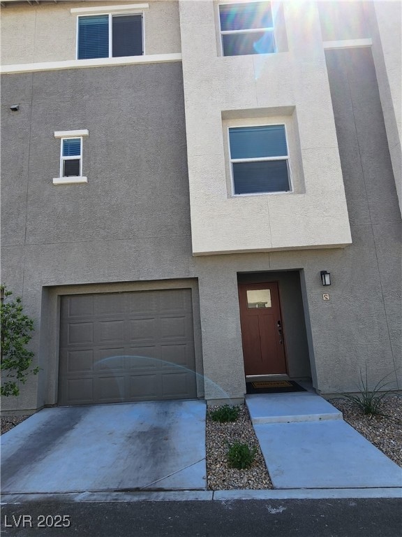 View of front facade featuring a garage and stucco