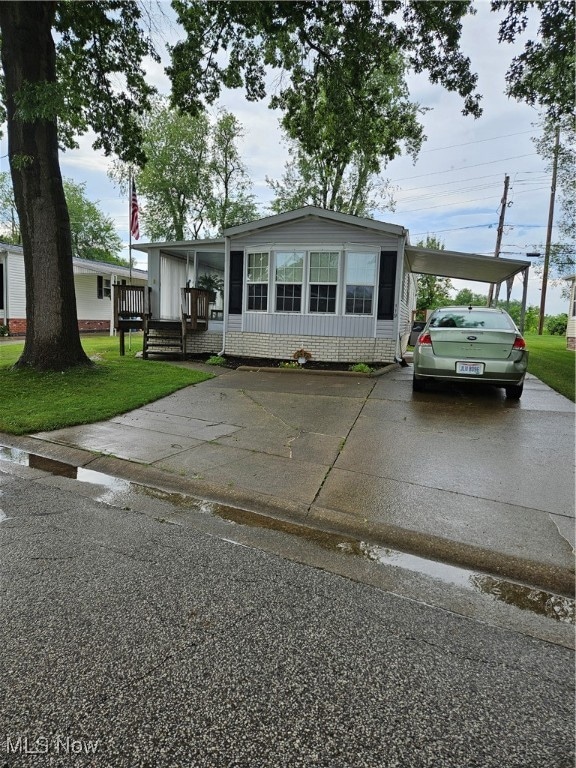 Manufactured / mobile home with a front lawn, an attached carport, and concrete driveway