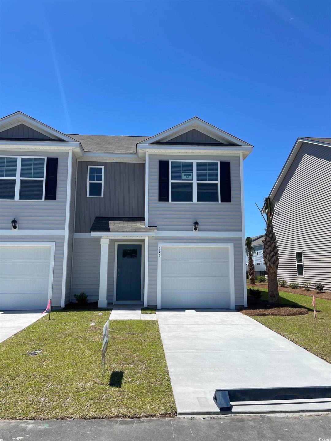 View of front facade featuring a garage, concrete driveway, a front lawn, and a shingled roof