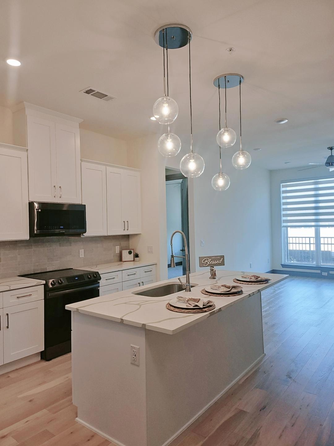 Kitchen with white cabinets, a sink, a kitchen isl