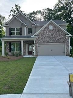 Craftsman house featuring driveway, a garage, stone siding, and a front lawn