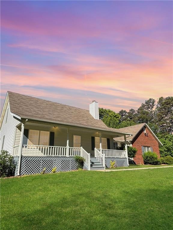 View of front of home with covered porch and a law