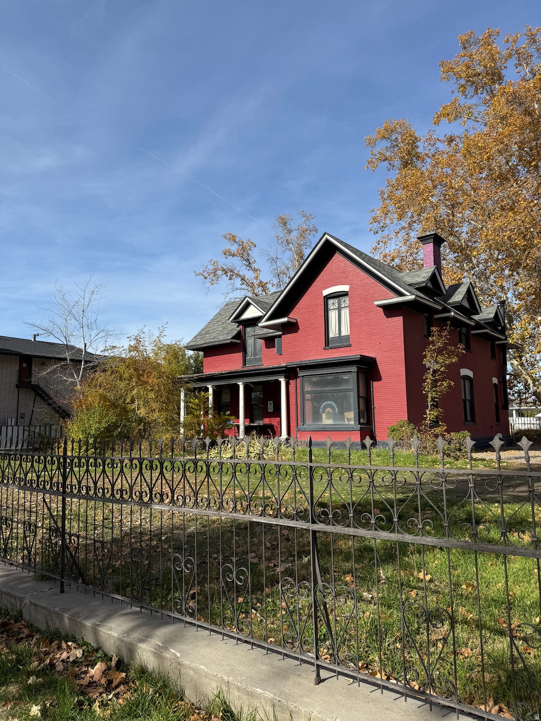 View of front of home with a fenced front yard, a chimney, covered porch, and brick siding
