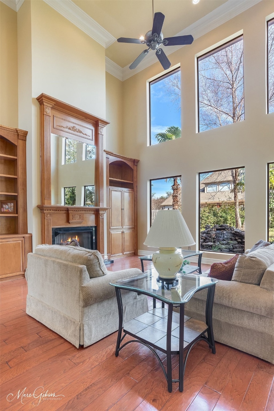 Living room featuring hardwood / wood-style flooring, ornamental molding, and a towering ceiling