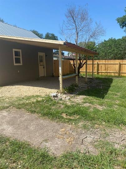 View of yard featuring fence and a carport
