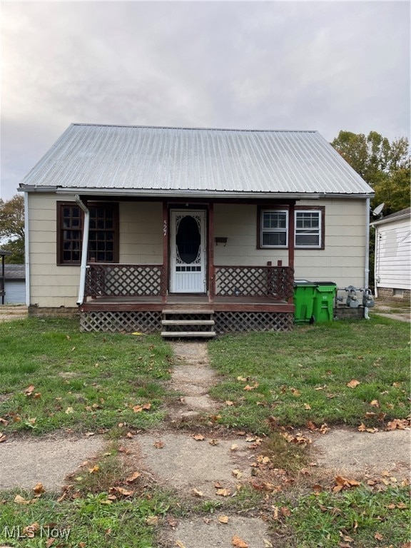 View of front of property with a front yard, covered porch, and a metal roof
